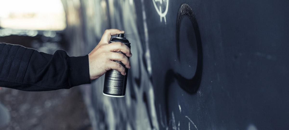 Мужчина рисует балончиком граффити на стене