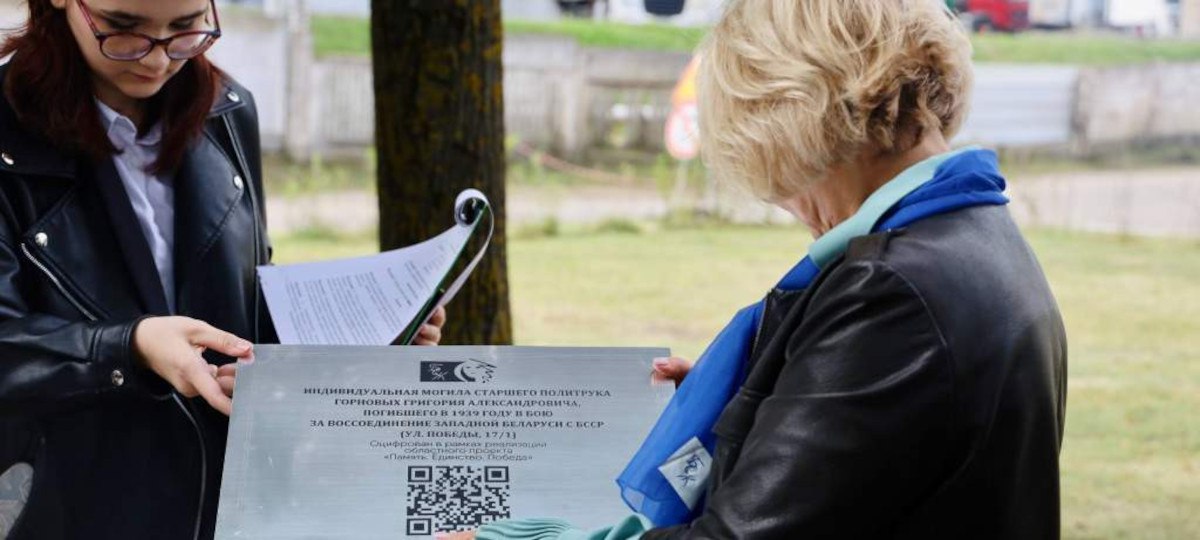 Две женщины рассматривают мемориальную табличку с QR-кодом