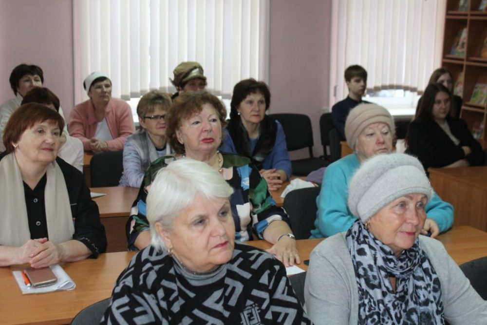 Люди пенсионного возраста сидят за столами 